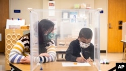 FILE - Pre-kindergarten teacher Sarah McCarthy works with a student at Dawes Elementary in Chicago, Jan. 11, 2021. 