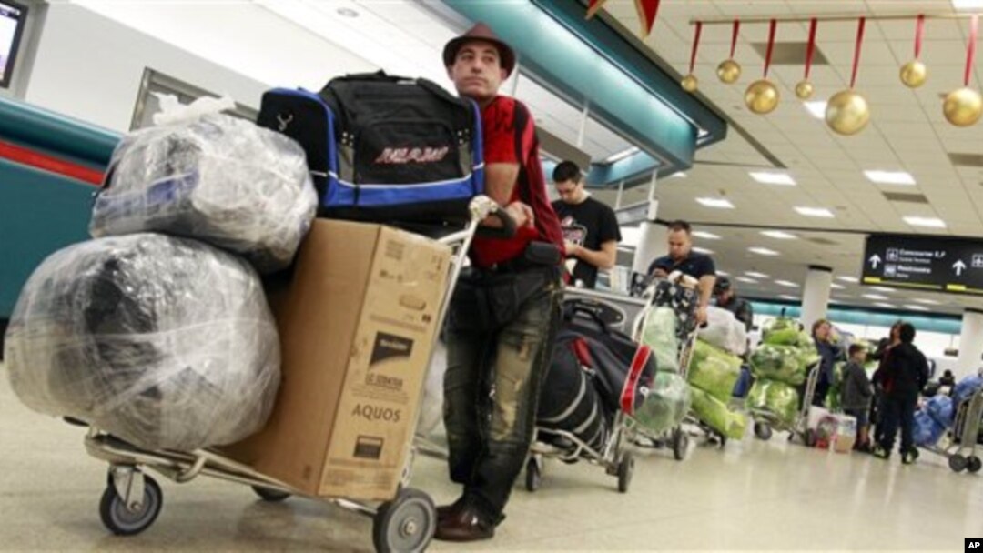 FILE - Travelers wait to check in for travel at Miami International Airport. The U.S. and Cuba reportedly are planning to resume regularly scheduled commercial flights.