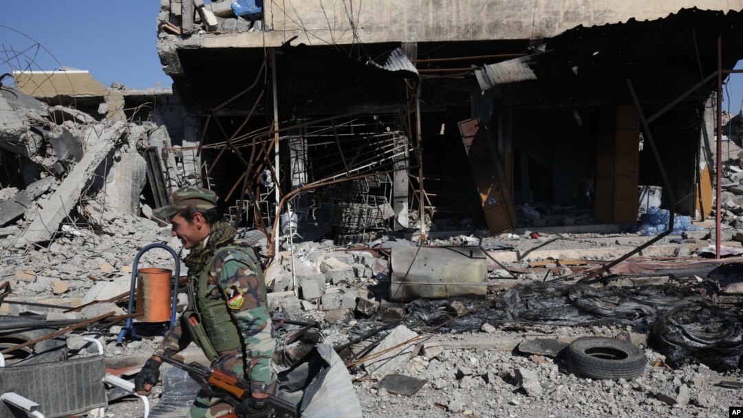 A Kurdish fighter walks past a destroyed building in the town of Sinjar on Nov. 13, 2015 after they took it from the Islamic State group in a joint operation with the coalition forces. 