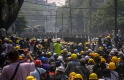 Anti-coup protesters, behind makeshift barricades stand off with Myanmar security forces in Yangon, Myanmar, March 2, 2021.