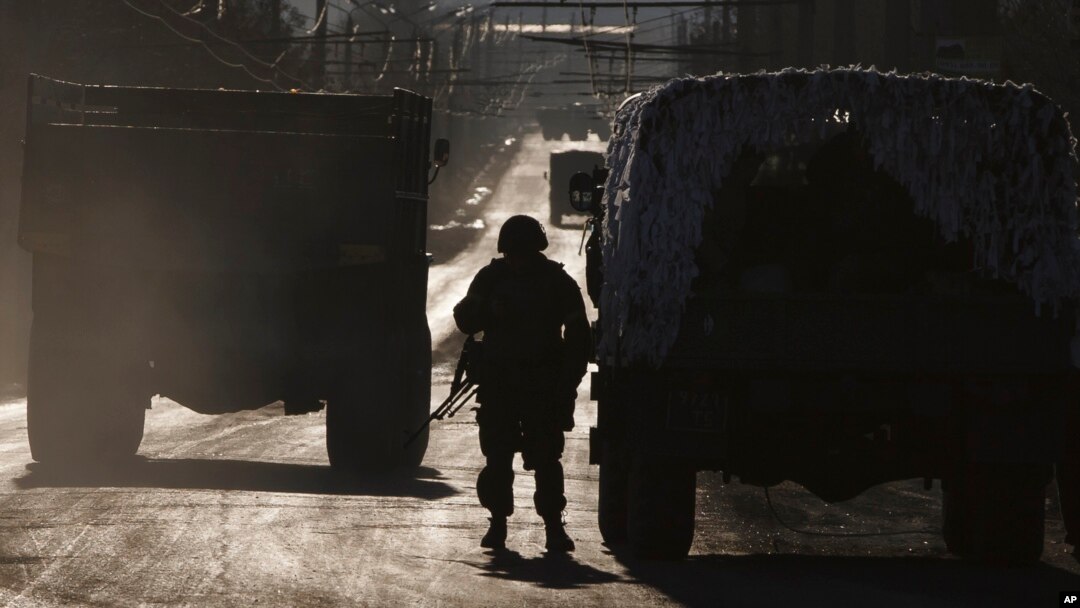 An Ukrainian soldier stands next to a broken down vehicle outside Artemivsk, Ukraine, as troops pull out of Debaltseve Feb. 18, 2015.