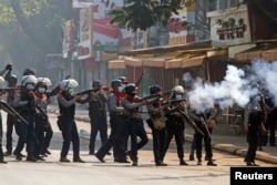 FILE - Riot police officers fire teargas canisters during a protest against the military coup in Yangon, Myanmar, Feb. 28, 2021.