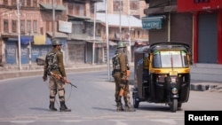 Indian police officer stop an auto-rickshaw after Kashmiri separatists called for a day-long strike against the recent killings in Kashmir, in downtown Srinagar, Apr. 2, 2018.