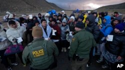 ARCHIVO - Agentes de la Patrulla Fronteriza de EEUU, hablan con migrantes procedentes de Colombia, China y Ecuador, en un campamento montañoso improvisado después de cruzar la frontera entre México y Estados Unidos, el viernes 2 de febrero de 2024, cerca de Jacumba, California. 