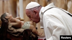 Pope Francis kisses a statue of baby Jesus as he leads the Christmas Eve mass in St. Peter's Basilica at the Vatican, Dec. 24, 2019.
