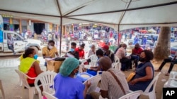 FILE - People wait to receive coronavirus vaccinations at a streetside vaccination tent in Kampala, Uganda, Sept. 7, 2021. Uganda is accelerating its vaccination drive and is now reaching out to people at bars and entertainment venues.