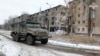 Un vehículo militar ruso pasa junto a edificios residenciales dañados durante el conflicto entre Rusia y Ucrania en la ciudad de Avdiivka en la región de Donetsk, Ucrania controlada por Rusia, en esta imagen tomada de un video publicado el 20 de febrero de 2024.