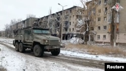 Rusko vojno vozilo prolazi pored stambenih zgrada oštećenih tokom borbenih dejstava, u gradu Avdejevka, u regionu Donjeck, u oblasti Ukrajine pod ruskom okupacijom, na fotografiji napravljenoj od video snimka, 20. februara 2024.