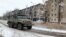 Un vehículo militar ruso pasa junto a edificios residenciales dañados durante el conflicto entre Rusia y Ucrania en la ciudad de Avdiivka en la región de Donetsk, Ucrania controlada por Rusia, en esta imagen tomada de un video publicado el 20 de febrero de 2024.