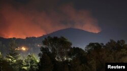 Kebakaran hutan meluas ke perbukitan di sekitar kota Toulumne, barat laut Taman Nasional Yosemite, California (28/8). Petugas pemadam kebakaran menurunnya suhu udara pada malam hari membantu mereka memadamkan api di wilayah ini.