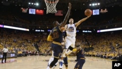 Stephen Curry (30) Golden State Warriors attaque avec le ballon face à LeBron James (23) de Cleveland Cavaliers au cours de la première mi-temps du deuxième match de la finale NBA de basket-ball à Oakland, en Californie., 5 juin 2016. (Ezra Shaw, Getty Images via AP, Pool