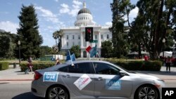 FILE - A supporter of a measure to limit when companies can label workers as independent contractors drives past the Capitol during a rally in Sacramento, Calif., Aug. 28, 2019.