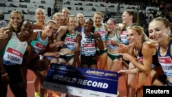 Kenya's Faith Kipyegon holds her new world record sign as she celebrates winning the women's 1500m final with athletes in Florence, Italy on June 2, 2023.