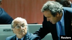 Michel Platini, président de l'UEFA, débout, discute avec Sepp Blatter, assis, à gauche, lors du 65e Congrès de la Fifa à Zurich, Suisse, le 29 mai 2015. 