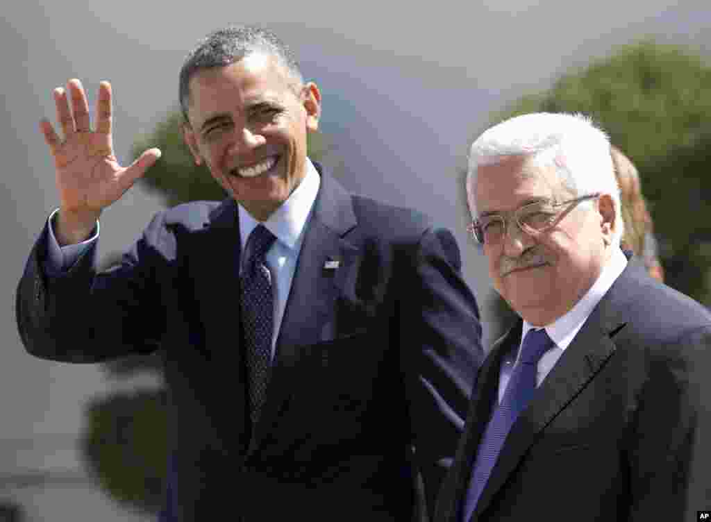 U.S. President Barack Obama waves to media as he walks with Palestinian President Mahmoud Abbas at the Muqata Presidential Compound in the West Bank town of Ramallah, March 21, 2013.
