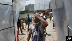 Un hombre con mascarilla camina por una cámara de descontaminación como medida preventiva antes de ingresar al mercado de alimentos de Coche en Caracas, Venezuela. Junio 11, 2020.