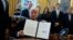 President Donald Trump shows his signature on an executive order on the Keystone XL pipeline, Jan. 24, 2017, in the Oval Office of the White House.