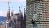 French urban climber, Alain Robert, also known as "French Spiderman", right, scales the 145 meters of the Agbar tower with the La Sagrada Familia Basilica designed by architect Antoni Gaudi in the background.