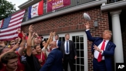Former President Donald Trump throws a football to the crowd during a visit to Iowa State University before a football game between Iowa State and the University of Iowa, Sept. 9, 2023, in Ames, Iowa.