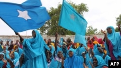Somali women wave their national flag at Konis stadium, in Mogadishu, during a ceremony marking the anniversary of Somalia’s independence, July 1, 2012. 