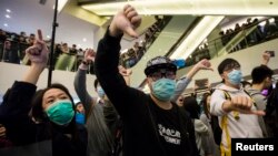 Protesters give thumbs-down signs to mainland Chinese travellers during a demonstration inside a shopping mall in Hong Kong, February 15, 2015.