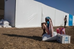 A Tigray refugee girl who fled the conflict in Ethiopia's Tigray region, sits on aid she received from the UNHCR and WFP at Umm Rakouba refugee camp in Qadarif, eastern Sudan, Nov. 24, 2020.