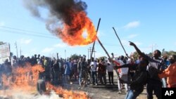 Rioters battle with Zimbabwean police in Harare, Monday, July, 4, 2016. Police in Zimbabwe's capital fired teargas and water cannons in an attempt to quell rioting by taxi and mini bus drivers protesting what they describe as police harassment. (AP Photo/Tsvangirayi Mukwazhi)