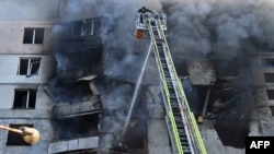 Para petugas SAR Ukraina sedang memadamkan api di gedung apartemen menyusul serangan rudal di Kharkiv di tengah invasi Rusia ke Ukraina, Minggu, 15 September 2024. (Foto: Sergey Bobok/AFP)