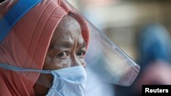 Seorang perempuan menggunakan pelindung wajah dan masker di sebuah stasiun seiring dengan pelonggaran pembatasan sosial di tengah pandemi virus corona (Covid-19) di Jakarta, 8 Juni 2020. (Foto: Reuters)