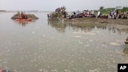 Penduduk desa berkumpul di tepi Sungai Yamuna dekat kota Baghpat di negara bagian Uttar Pradesh, India, saat regu penyelamat beruoaya melakukan pencarian korban kapal terbalik di sungai tersebut, Kamis, 14 September 2017. 