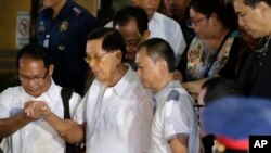 Senator Filipina Juan Ponce Enrile (kedua dari kiri) dibantu menuruni tangga menuju ambulan setelah mengikuti penyidikan di kantor polisi Filipina terkait tuduhan penggelapan. 