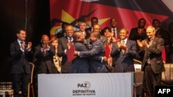 Mozambique's President Filipe Nyusi, center left, and Renamo (Mozambican National Resistence) leader Ossufo Momade hug after signing a cease-fire agreement in Maputo, Mozambique, Aug. 6, 2019. 