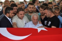 FILE - Relatives of Osman Kose, a 38-year-old Turkish diplomat killed in Iraq, mourn in front of the coffin covered with a Turkish National flag, during the funeral ceremony in Ankara, July 18, 2019.