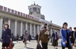 FILE - People wearing protective face masks walk amid concerns over the new coronavirus disease (COVID-19) in front of Pyongyang Station in Pyongyang, North Korea April 27, 2020, in this photo released by Kyodo.