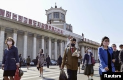 FILE - People wearing protective face masks walk amid concerns over the new coronavirus disease (COVID-19) in front of Pyongyang Station in Pyongyang, North Korea April 27, 2020, in this photo released by Kyodo.