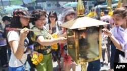 Women light incense sticks before offering prayers at the reopened Erawan shrine - the popular tourist site where 20 people were killed on August 17 in a bomb blast - in central Bangkok on Aug. 20, 2015. 