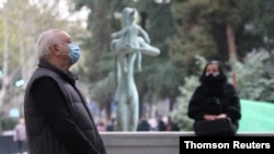 A man wearing a protective face mask waits in line to enter a polling station during a parliamentary election in Tbilisi, Georgia, Oct. 31, 2020.