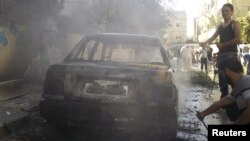 Residents stand next to a damaged car after shelling by forces loyal to Syria's President Bashar al-Assad at al-Saad near Deraa, November 3, 2012. 