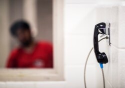 A detainee waits for a visit from family who must communicate through a phone at the Stewart Detention Center in Lumpkin, Ga., Nov. 15, 2019.