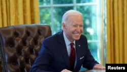 El presidente Joe Biden sonríe a los periodistas tras firmar dos acciones ejecutivas en la Casa Blanca, el 28 de enero de 2021.