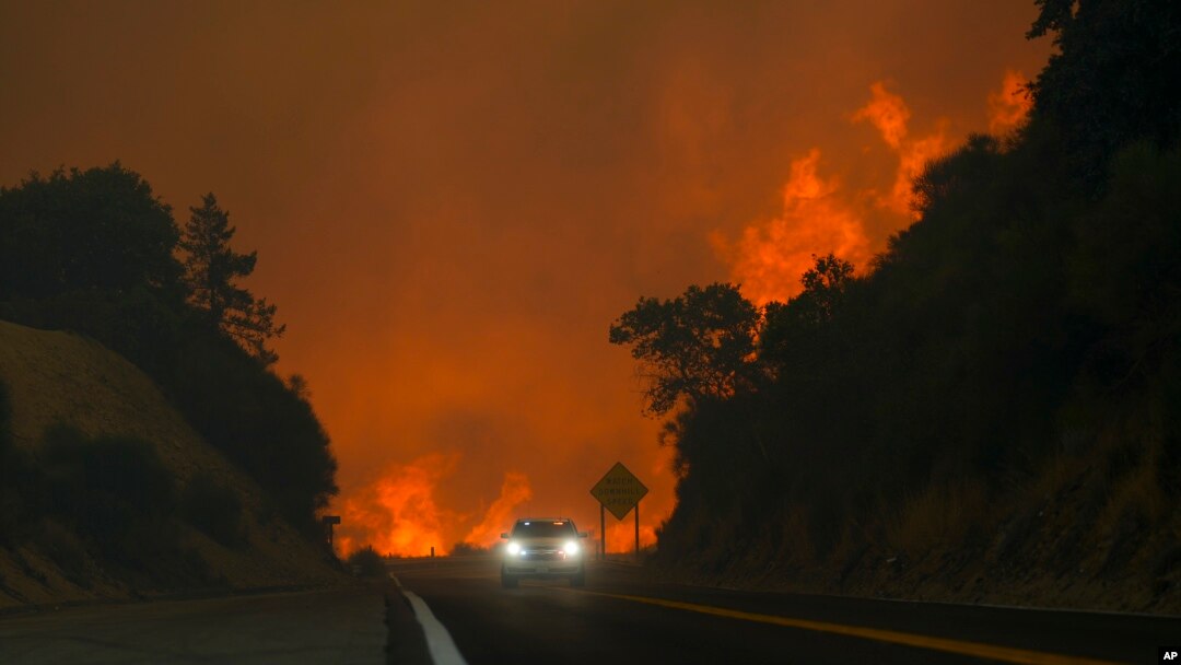 The Line Fire jumps highway 330 as a motorist speeds past, Sept. 7, 2024, near Running Springs, California.