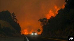 The Line Fire jumps highway 330 as a motorist speeds past, Sept. 7, 2024, near Running Springs, California.