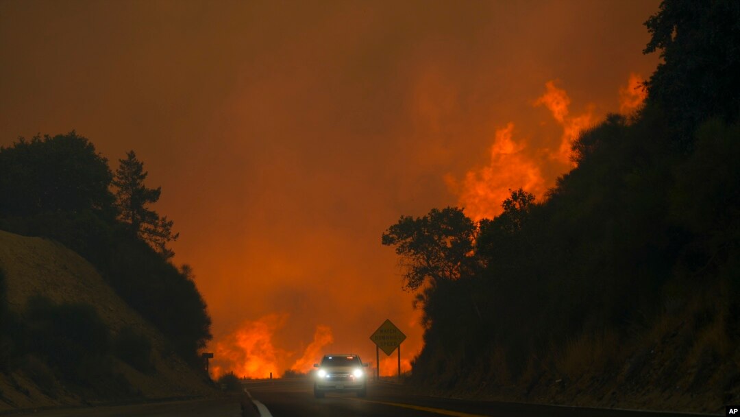 El incendio conocido como Line Fire salta la autopista 330 mientras un automovilista pasa a toda velocidad, el 7 de septiembre de 2024, cerca de Running Springs, California.