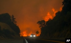 The Line Fire jumps highway 330 as a motorist speeds past, Sept. 7, 2024, near Running Springs, California.