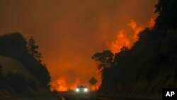 El incendio conocido como Line Fire salta la autopista 330 mientras un automovilista pasa a toda velocidad, el 7 de septiembre de 2024, cerca de Running Springs, California.