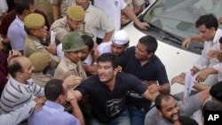 Police try to remove supporters of veteran Indian social activist Anna Hazare who were attempting to block the vehicle carrying Hazare after he was arrested by police in New Delhi, Aug. 16, 2011.