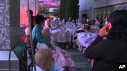 视频截图显示，在2018年8月13日星期一发生火灾后，患者留在台湾新北市的卫生和福利部台北医院外面。