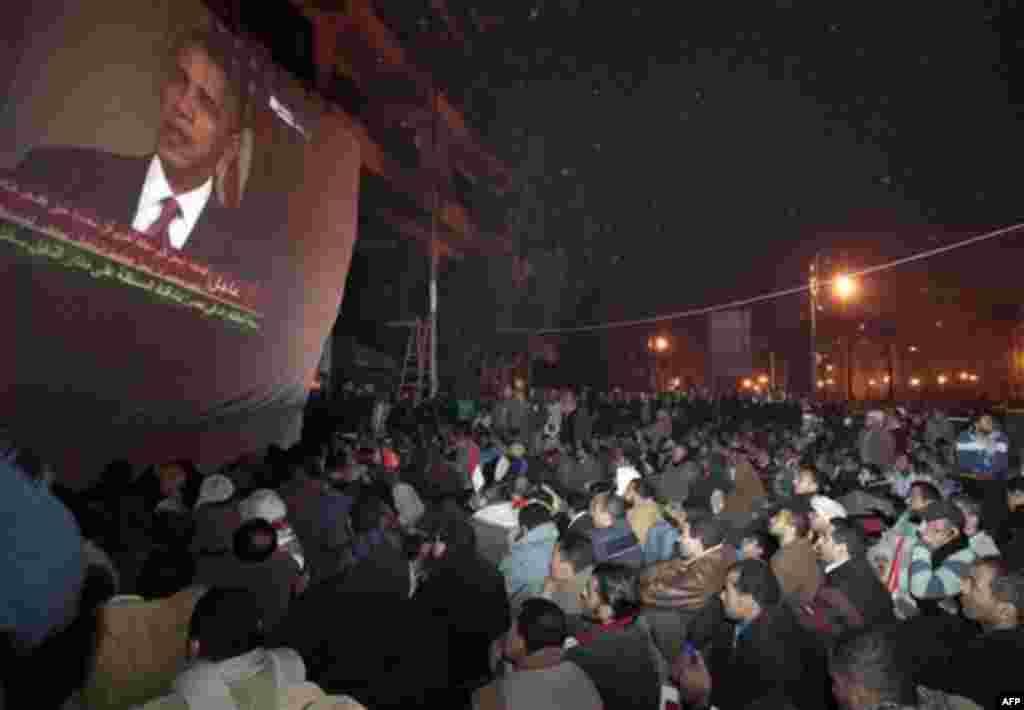 Egyptian anti-government protesters gathered in Tahrir (Liberation) square, watch a screen showing U.S. President Barack Obama live on a TV broadcast from Washington DC, speaking about the situation in Egypt, early Wednesday, Feb. 2, 2011. (AP Photo/Lefte