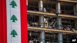 A banner with representations of the Lebanese flag hangs on a damaged building in a neighborhood near the site of last week's explosion that hit the seaport of Beirut, Lebanon, August 12, 2020.