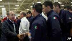Handout picture provided by the Mexican Presidency shows Mexican President Felipe Calderon (L) shaking hands with workers during a tour at the new Chrysler automaker plant in Saltillo, Cohauila state, Mexico, 29 Oct 2010